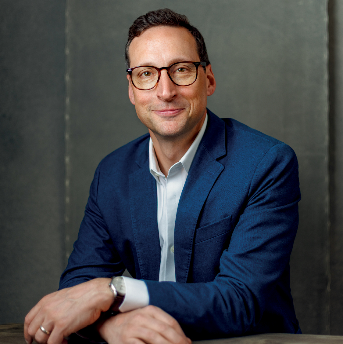 A white man wearing glasses and a blue suit