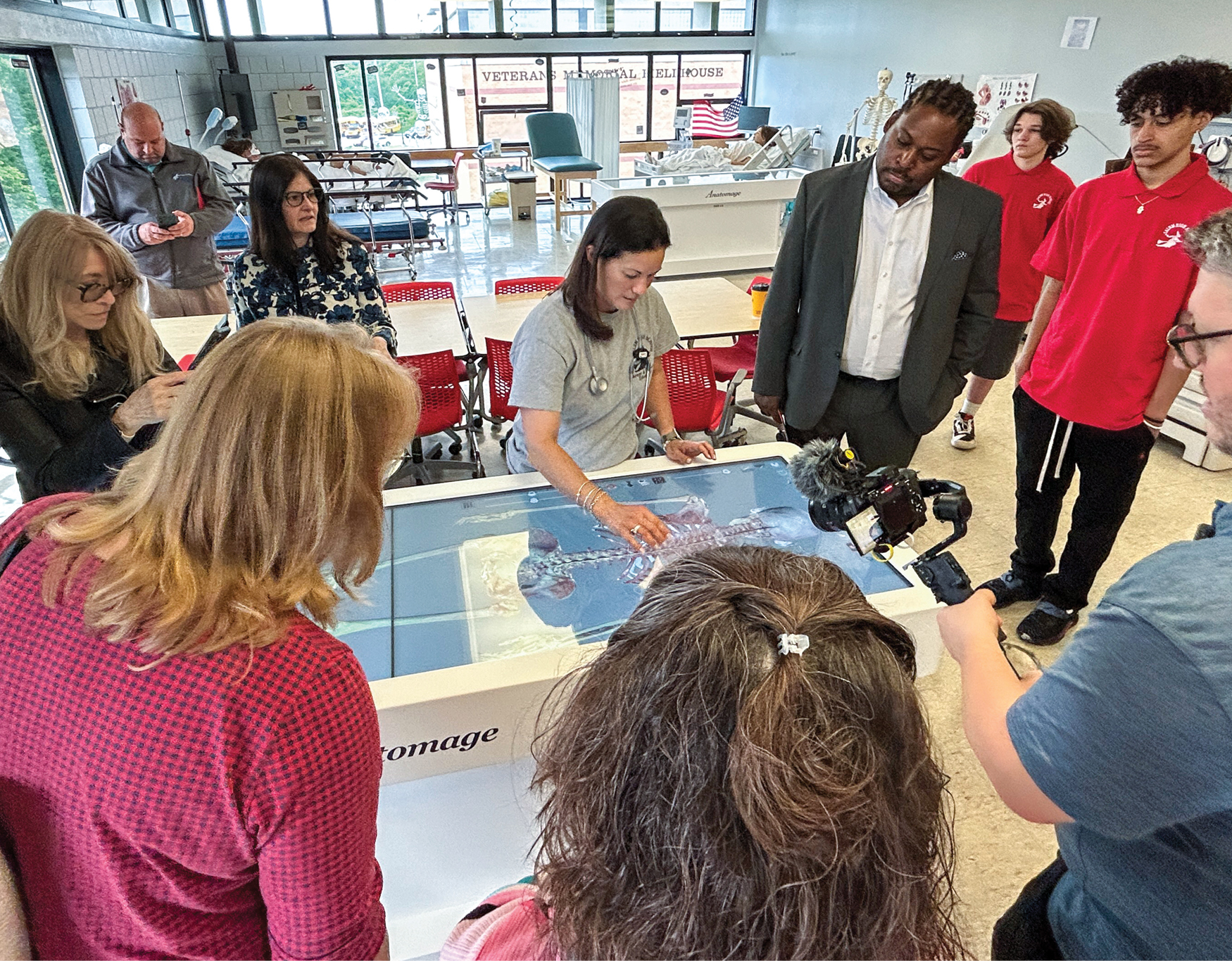 A group of people standing over a virtual anatomy