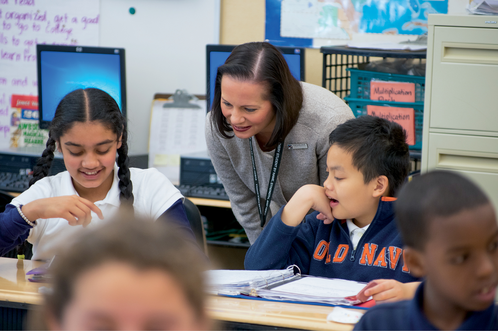 A white woman bends down over a table with children learning