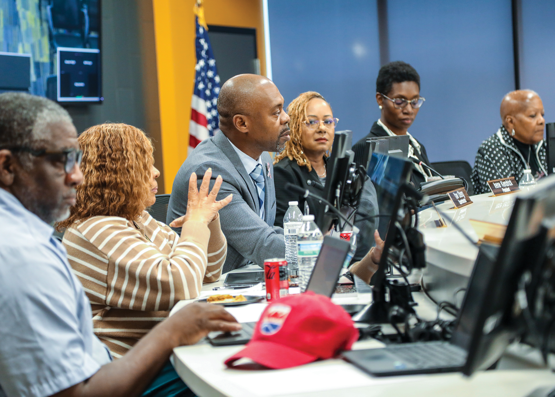A large group sitting at a long table with microphones in front of them