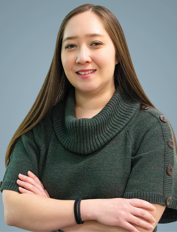 An Asian woman smiling and crossing her arms headshot