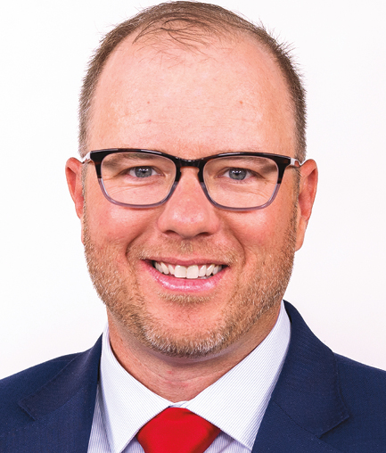 A man with light brown hair wearing glasses and a suit headshot