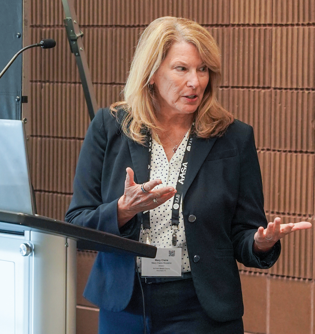 A white woman wearing a suit giving a presentation talking with her hands