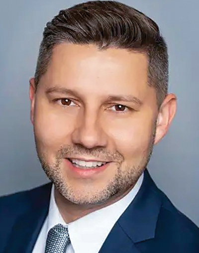 A white man smiling and wearing a suit headshot