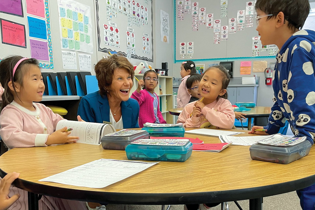 A woman laughing at a round table with young children