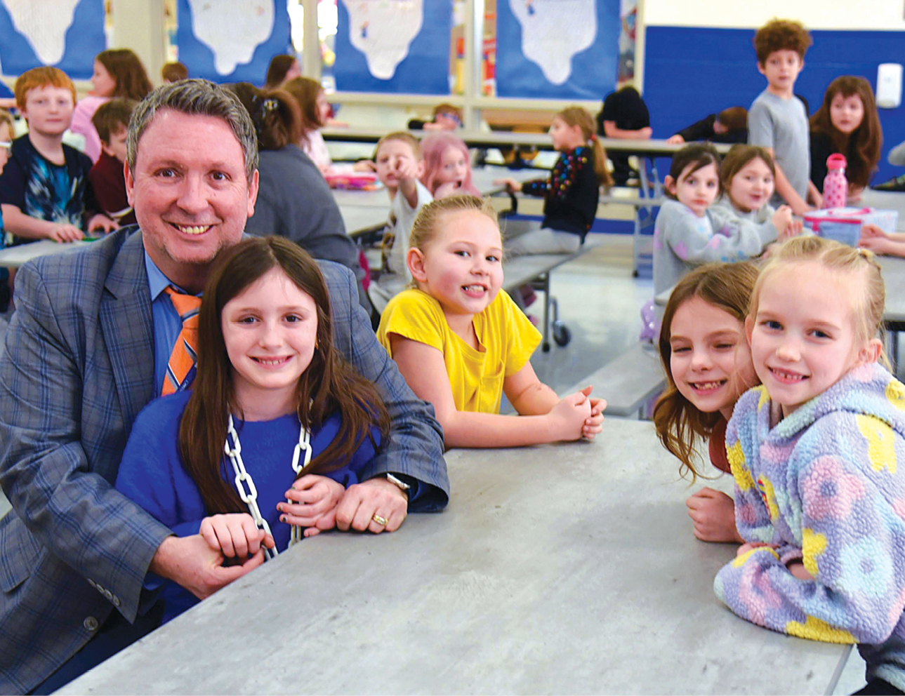 A white man sitting at a table with a group of young children