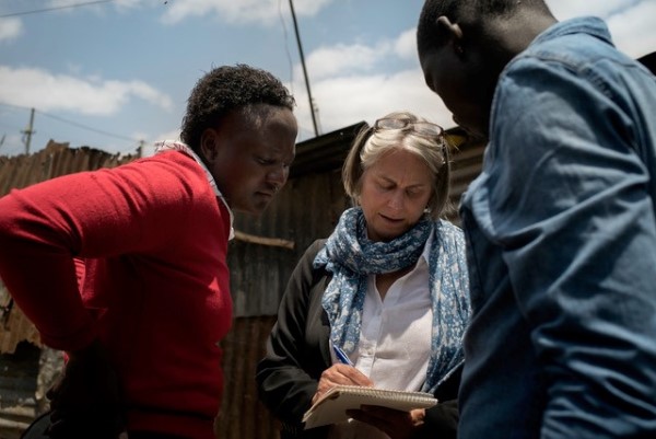Peg Tyre writes on a notepad while consulting with two others