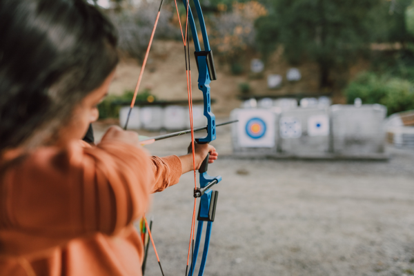 girl shooting bow and arrow at target